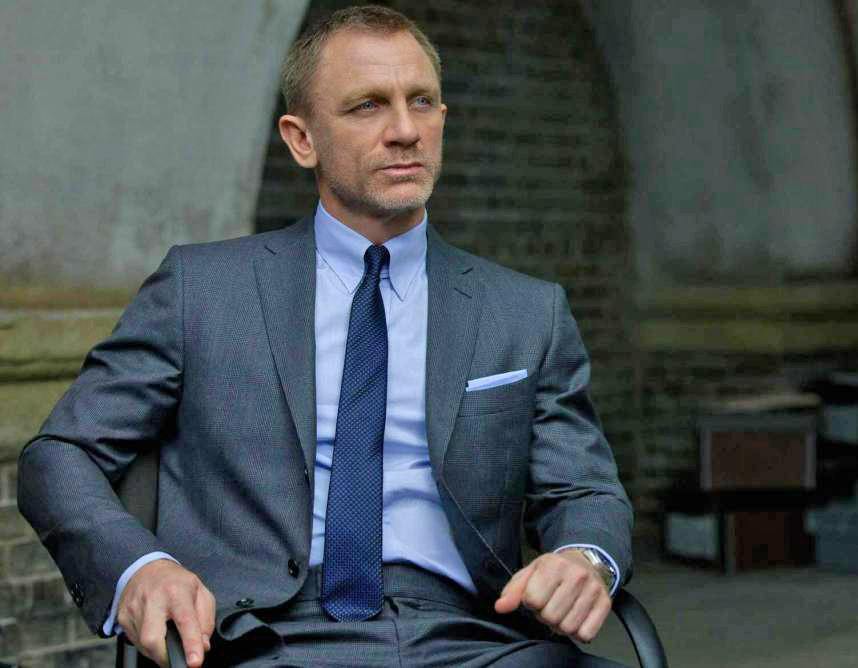 James Bond wears grey suit, light blue shirt and blue tie