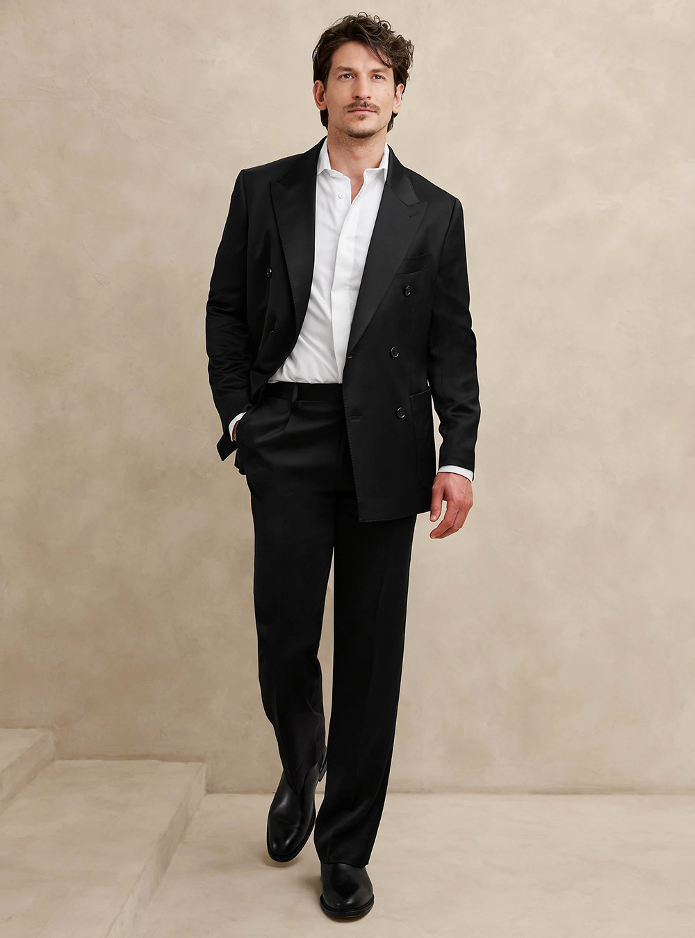 black double-breasted suit, white dress shirt, and black leather Chelsea boots