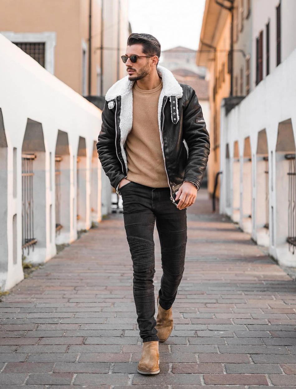 Black shearling jacket, tan sweater, black jeans, and brown Chelsea boots