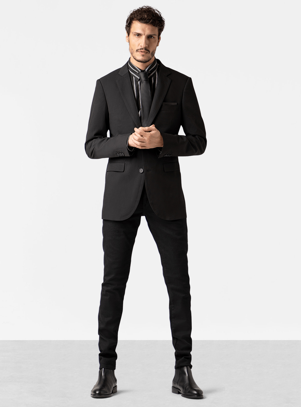Black suit jacket, black and white dress shirt, black jeans, black tie and black Chelsea boots