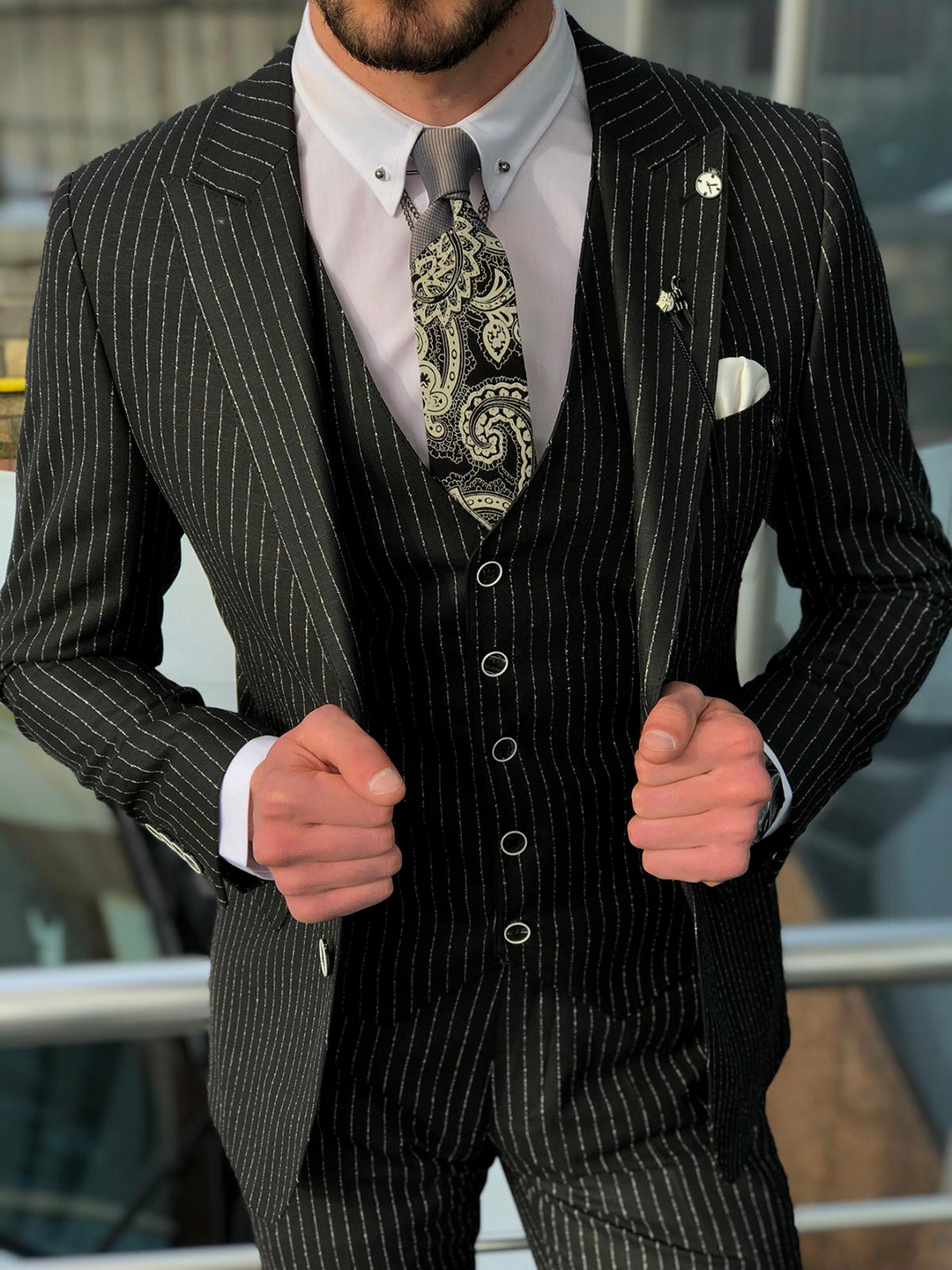 black three-piece pinstripe suit with a paisley tie