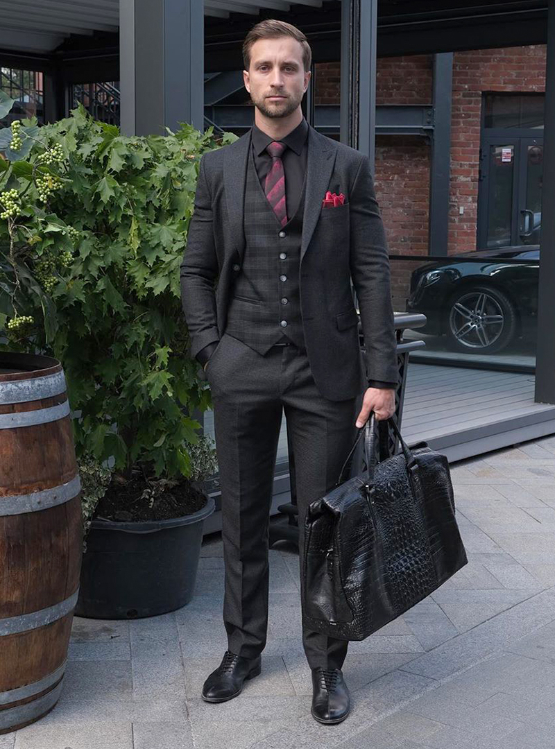 Black three-piece suit, black dress shirt, burgundy horizontal striped tie and black oxford shoes