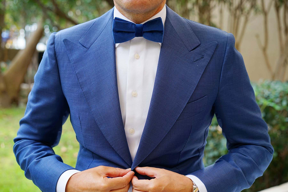 blue suit with a white shirt and blue bow tie