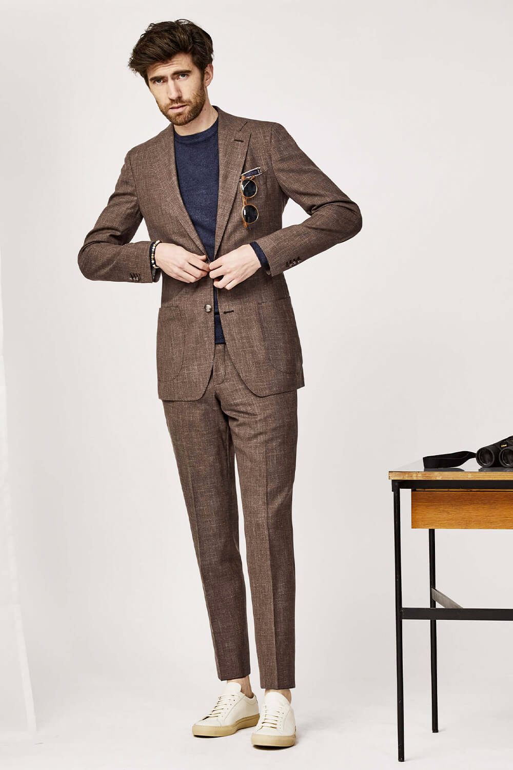 brown linen suit, navy t-shirt, and white sneakers