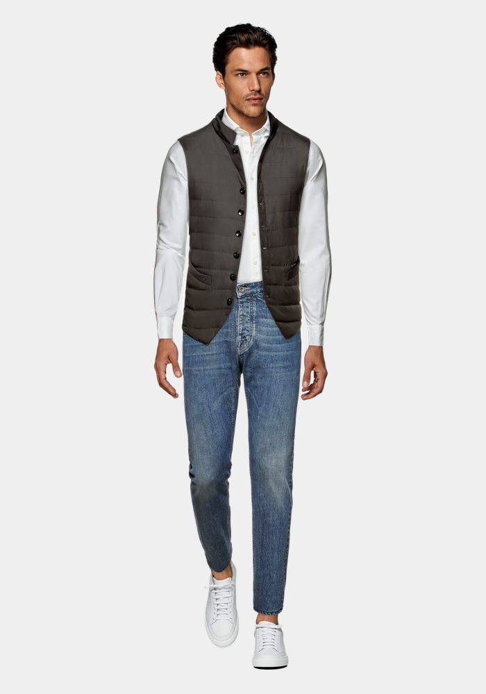 brown quilted vest, white button down shirt, and blue jeans