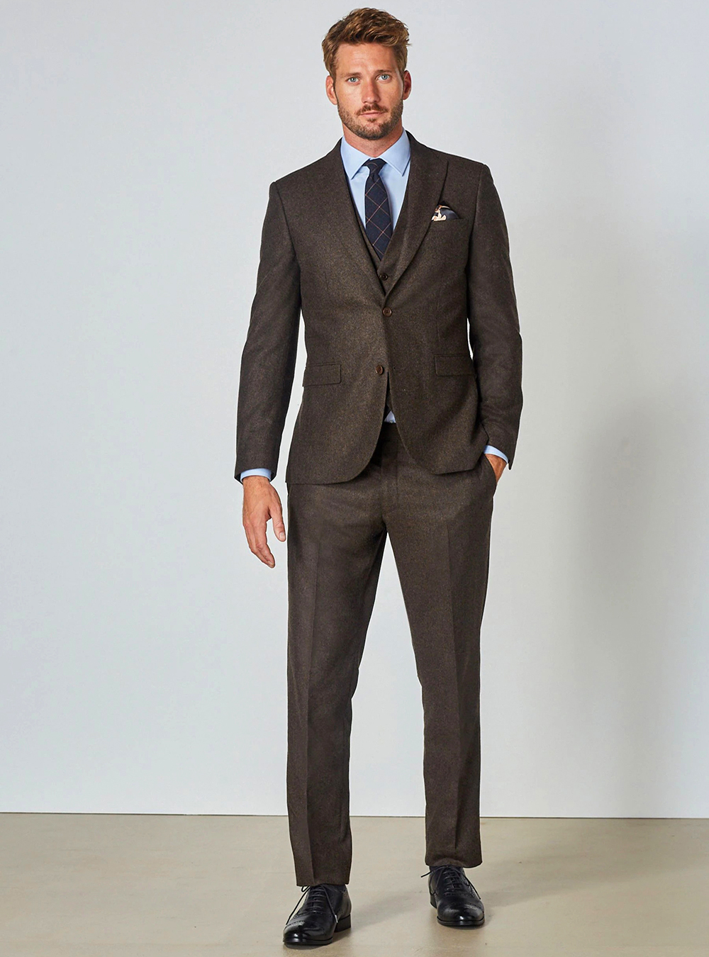 Brown three-piece suit, blue dress shirt, navy tie and black brogues