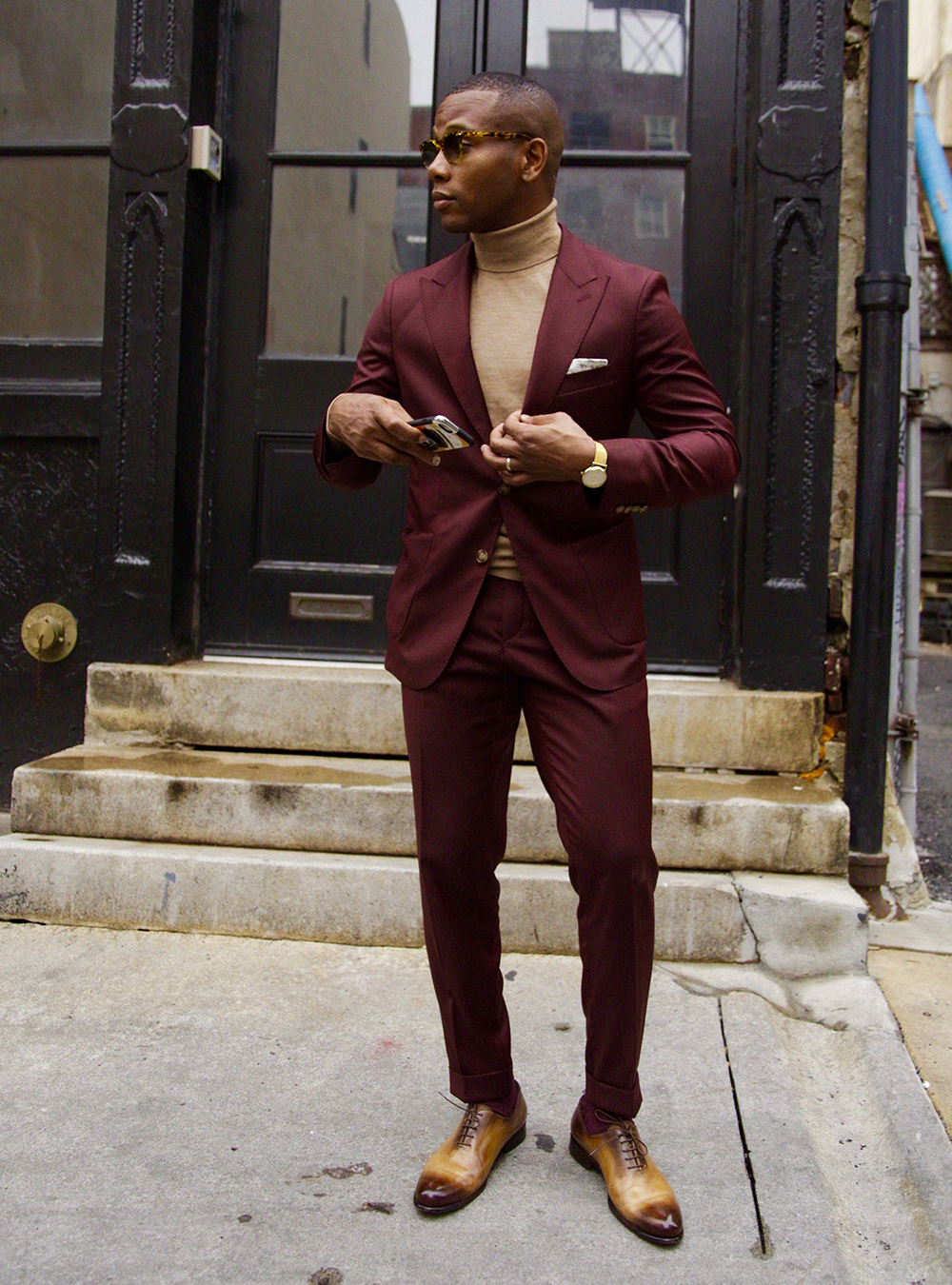 burgundy suit, light brown turtleneck, and tan oxford shoes