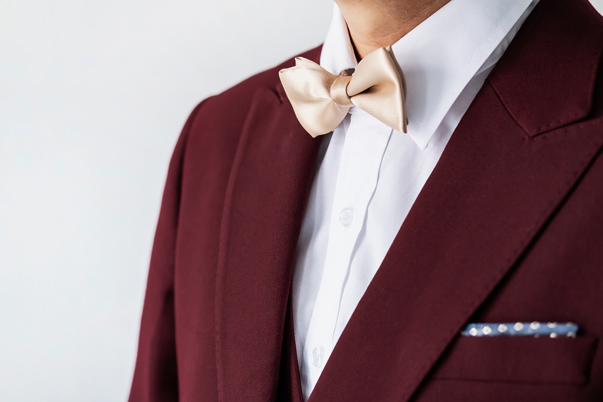 burgundy suit with a white shirt and tan bow tie