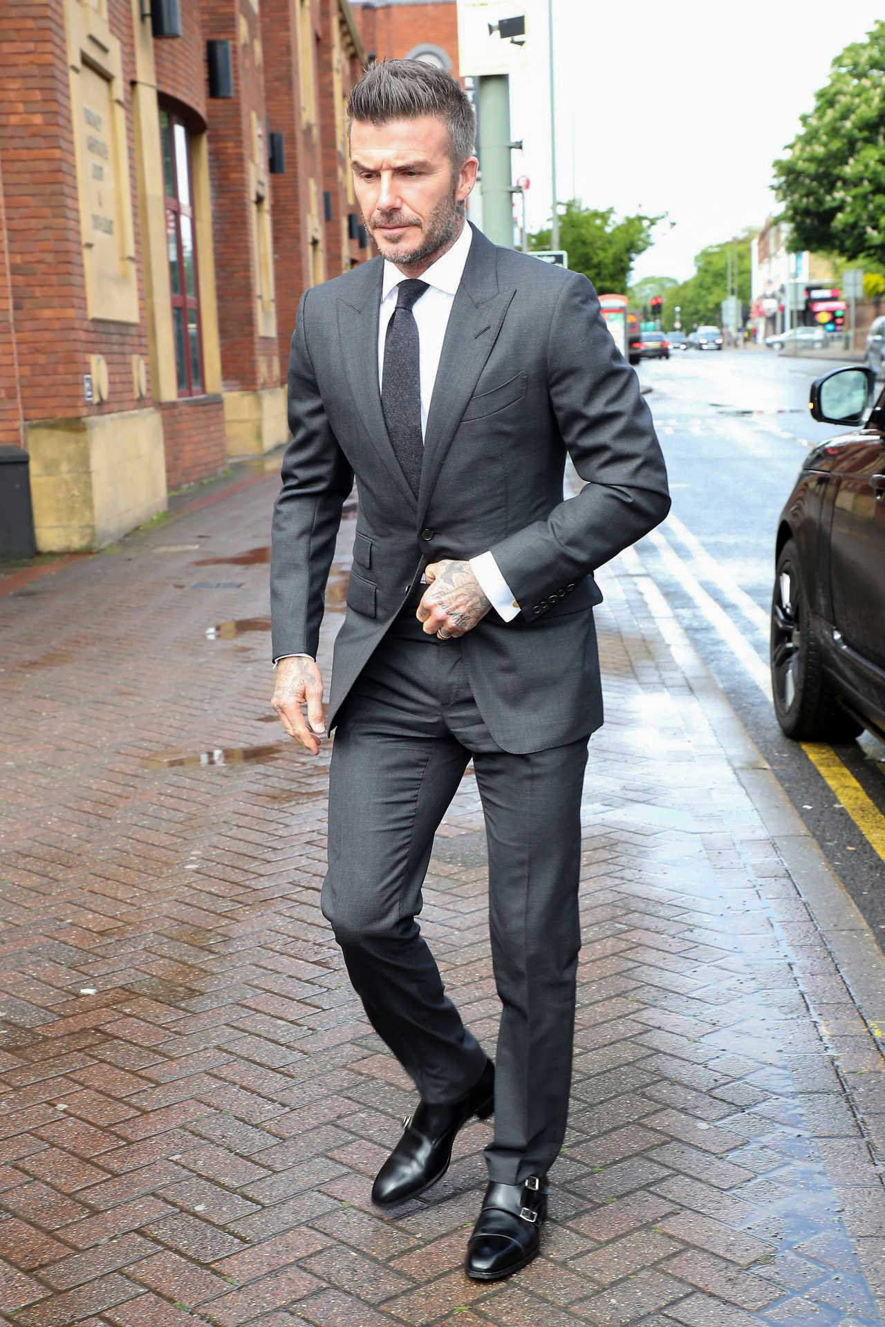 Beckham in charcoal suit, white shirt, and black monks
