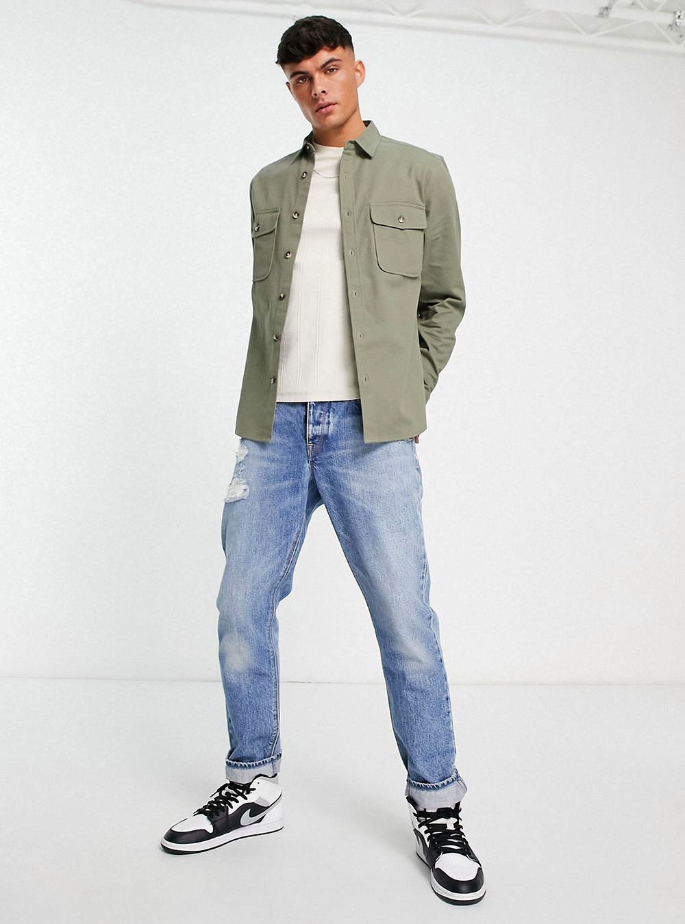 green shirt jacket, white t-shirt, blue jeans, and sneakers