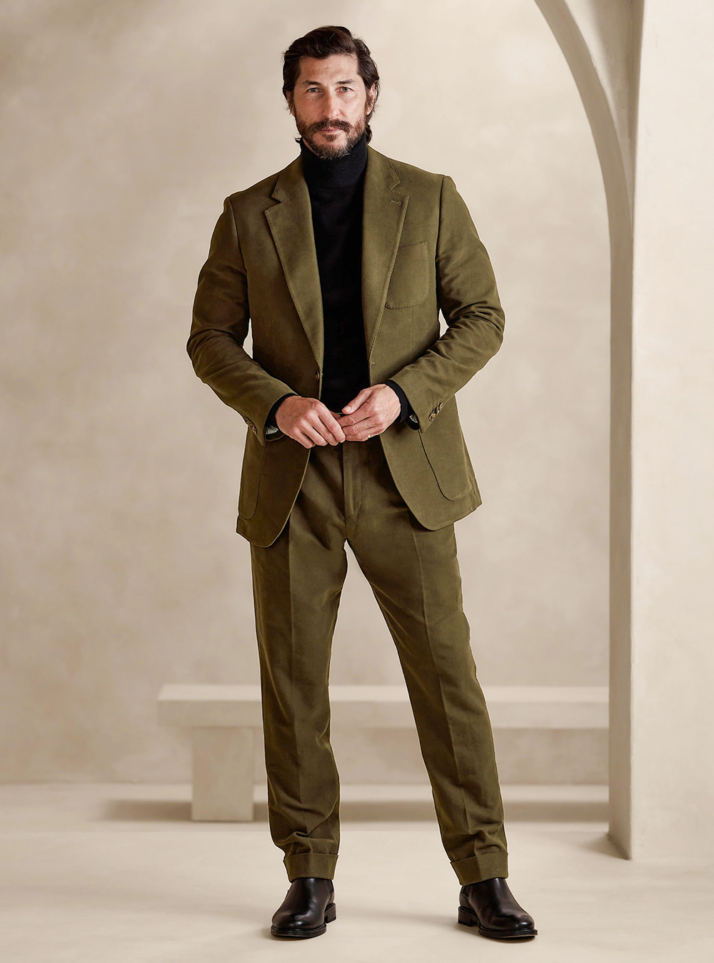 Green suit, black turtleneck and black leather Chelsea boots
