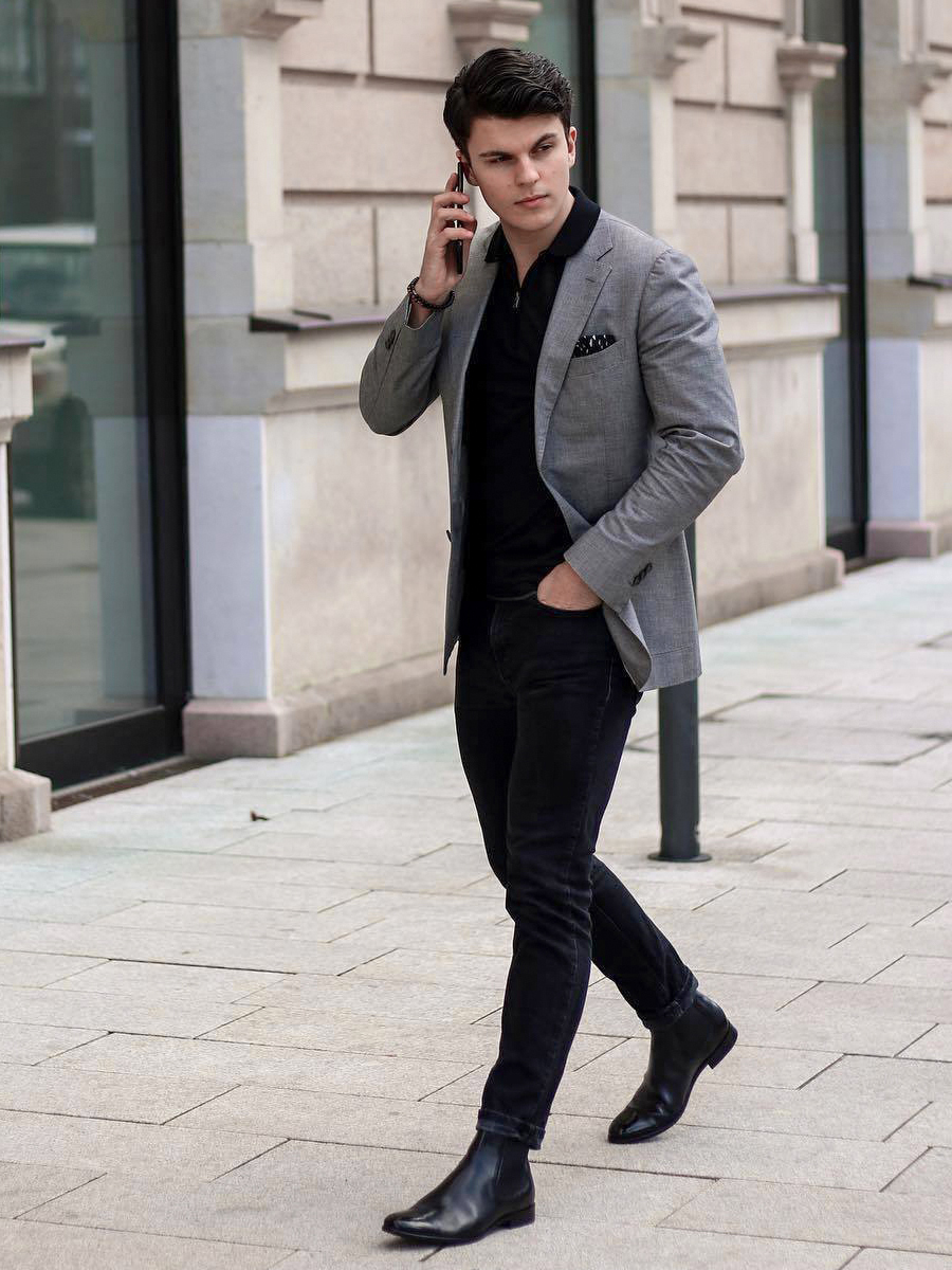 grey blazer, black polo shirt, and dark jeans