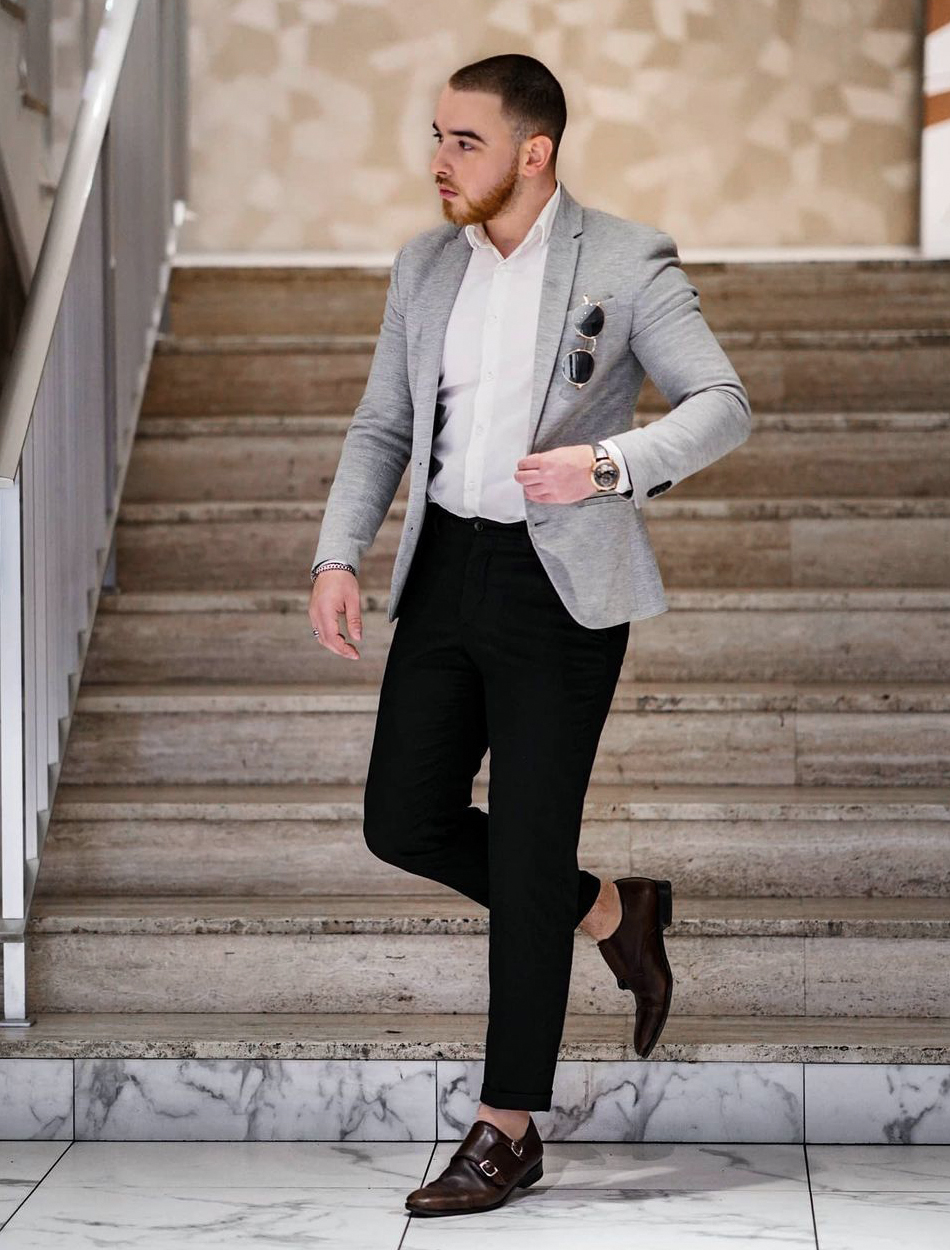 grey blazer and black pants with a white shirt and brown monks
