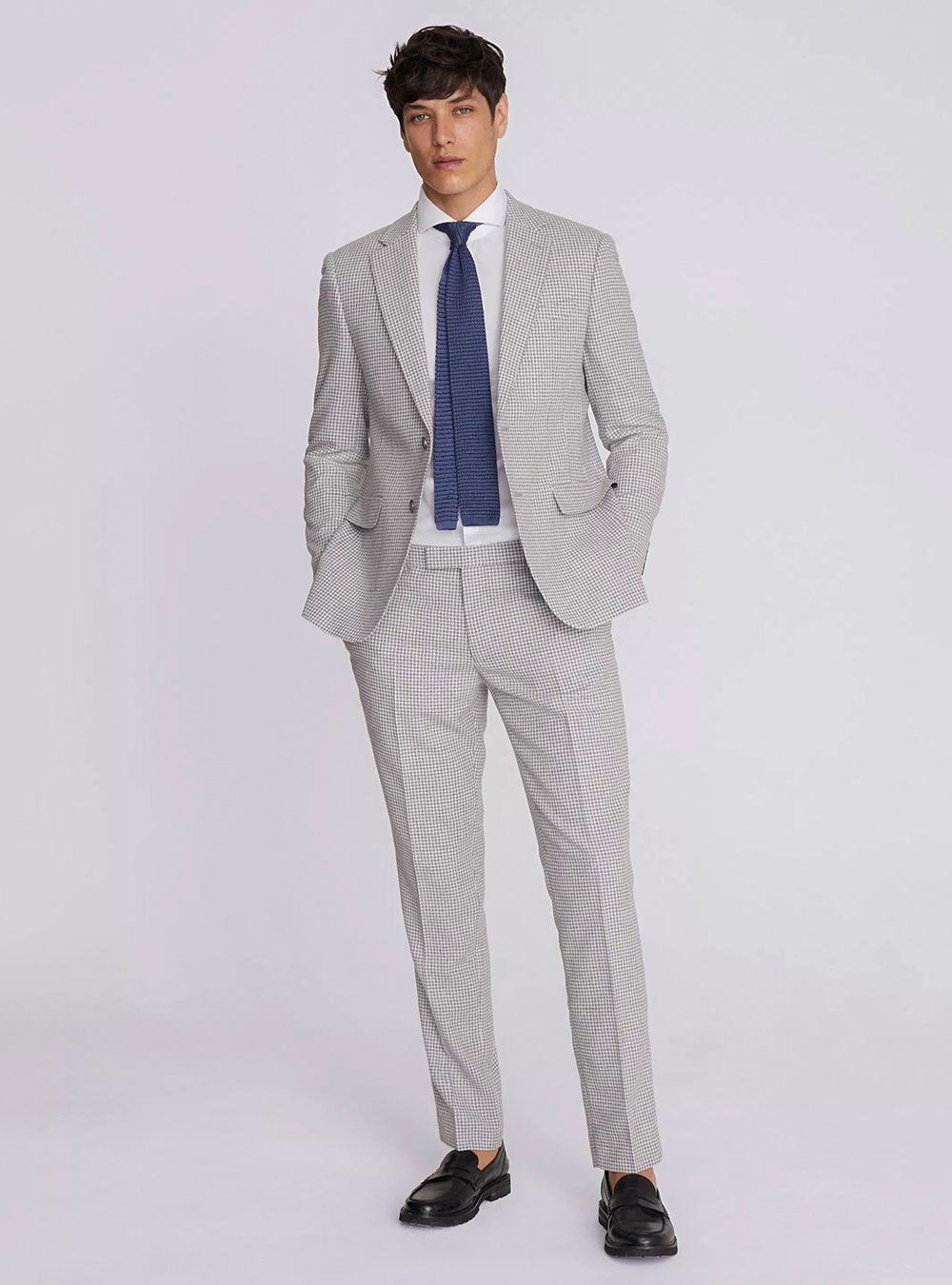 Grey houndstooth suit, white dress shirt, blue tie and black loafers