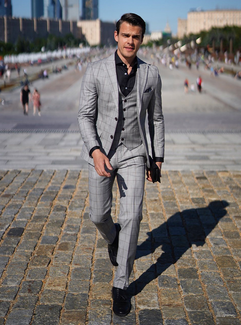 grey three-piece suit, black shirt, and black derby shoes