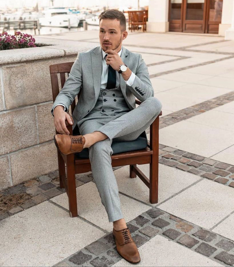 wearing a grey suit with a white shirt and brown shoes