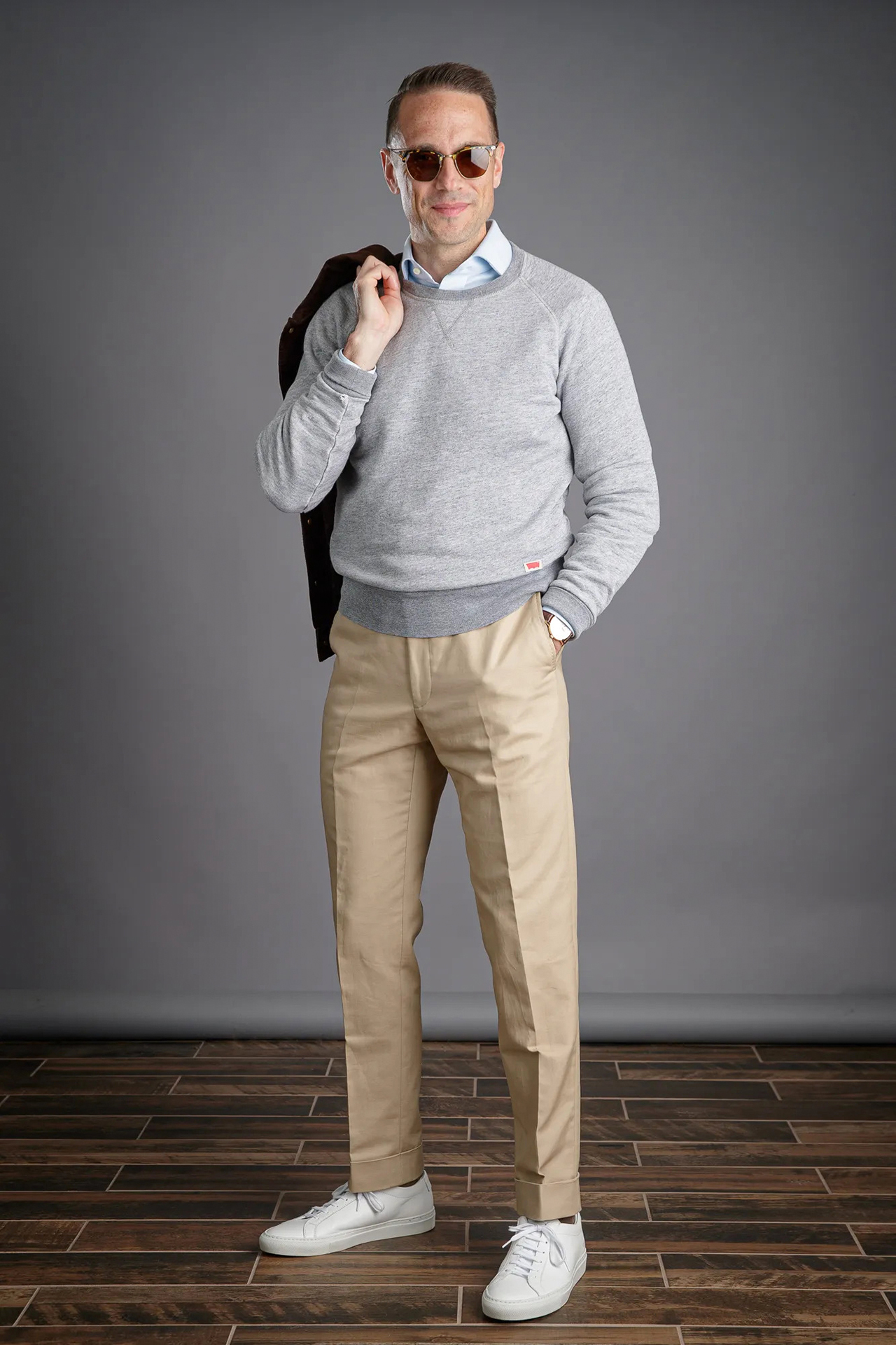 grey sweater, light blue shirt, khaki chinos, and white sneakers