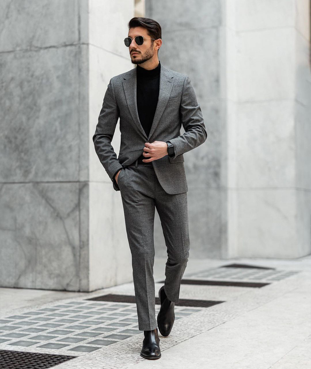 grey suit, black turtleneck sweater, and black Chelsea boots