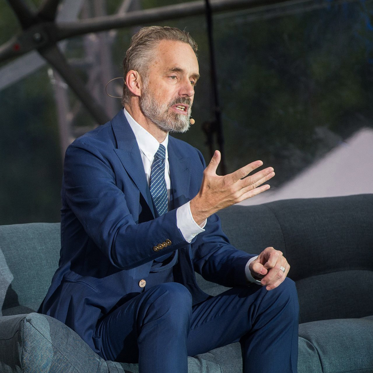 Peterson in a navy suit, white shirt, and navy patterned tie