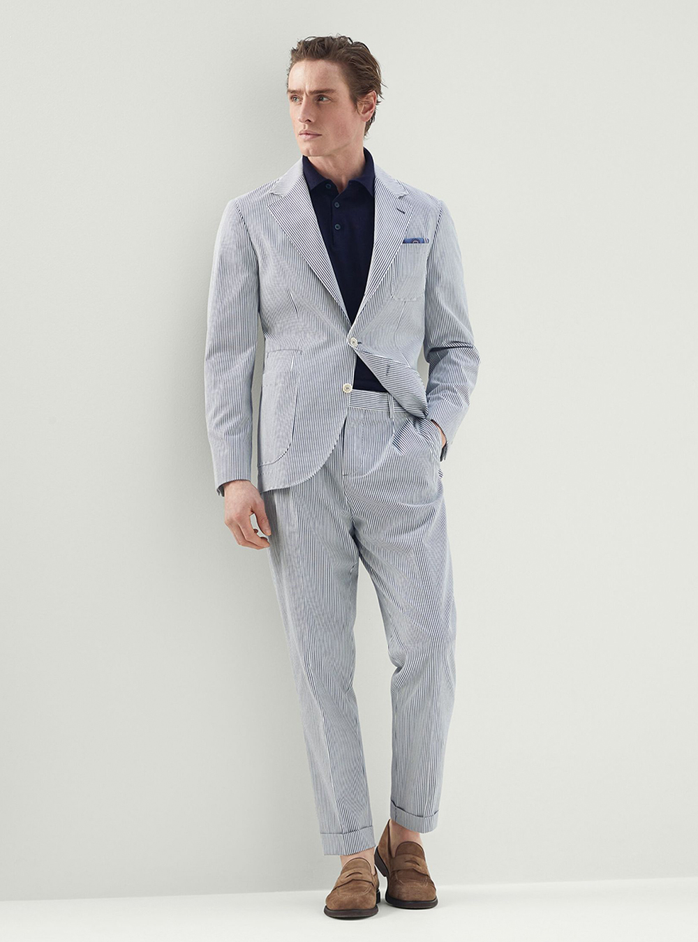 light grey seersucker suit, navy polo t-shirt, and brown suede loafers