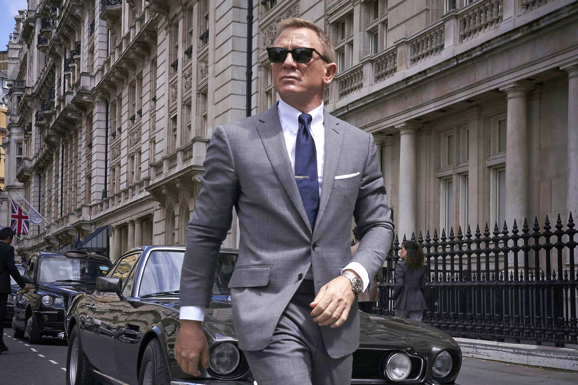 James Bond (Daniel Craig) in a light-grey suit and black wayfarers