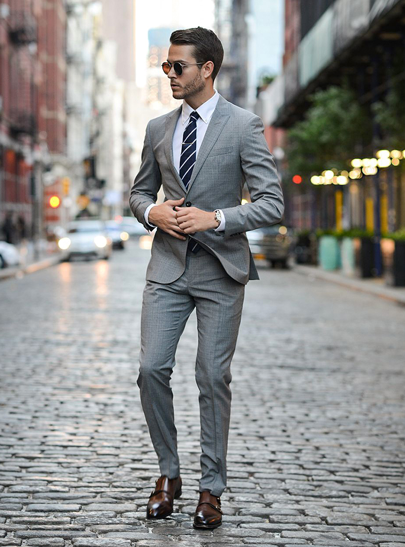 light grey suit, white shirt, navy tie, and brown monk straps