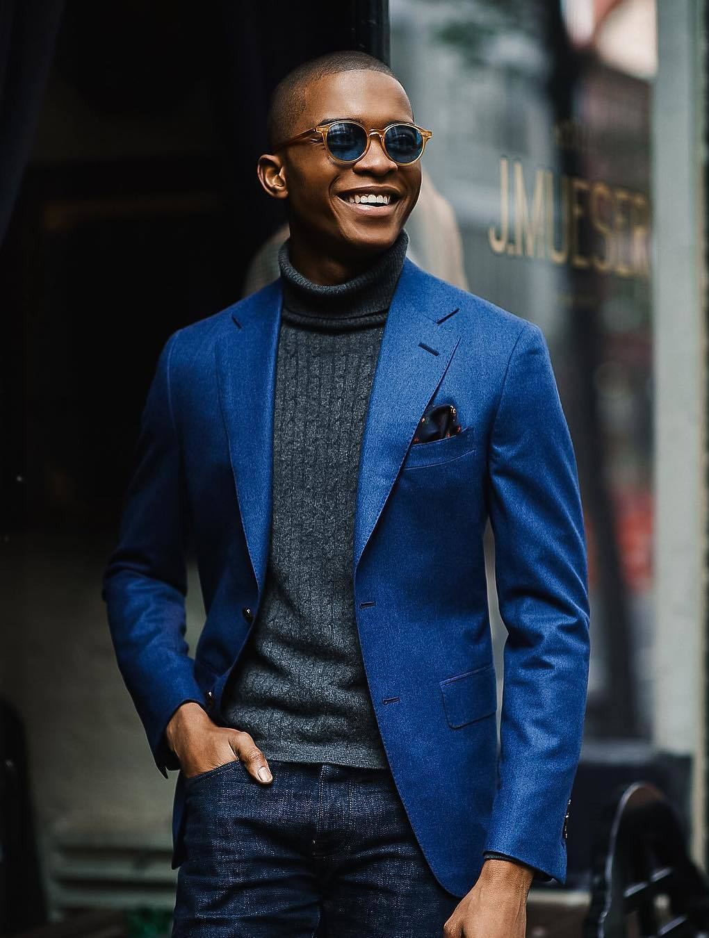 Matching a blue suit jacket, grey turtleneck, and dark blue jeans