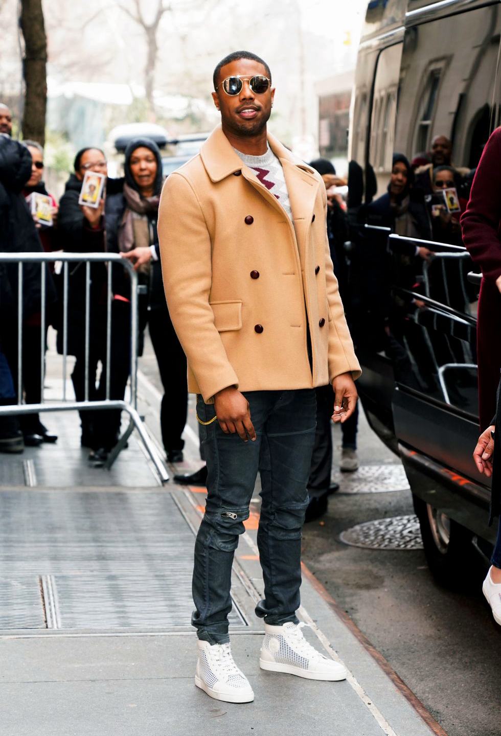 camel pea coat, dark jeans, beige sweater, and white sneakers