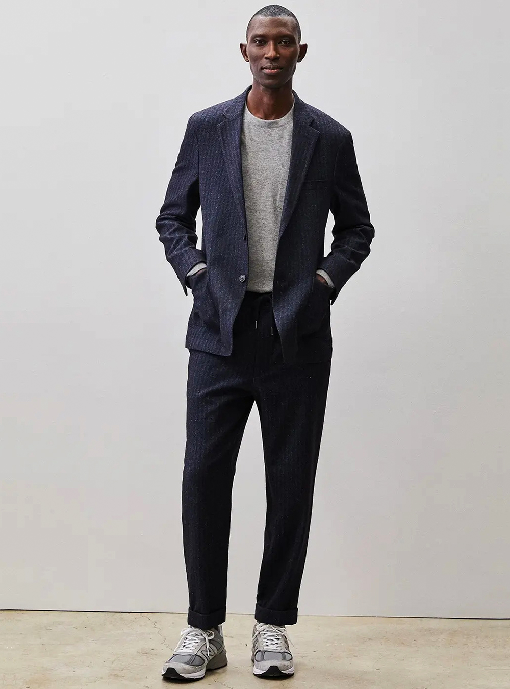 Navy blue pinstripe suit, grey t-shirt, and grey runners