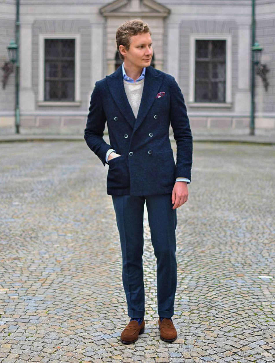 navy pea coat with tan crew neck sweater and blue shirt