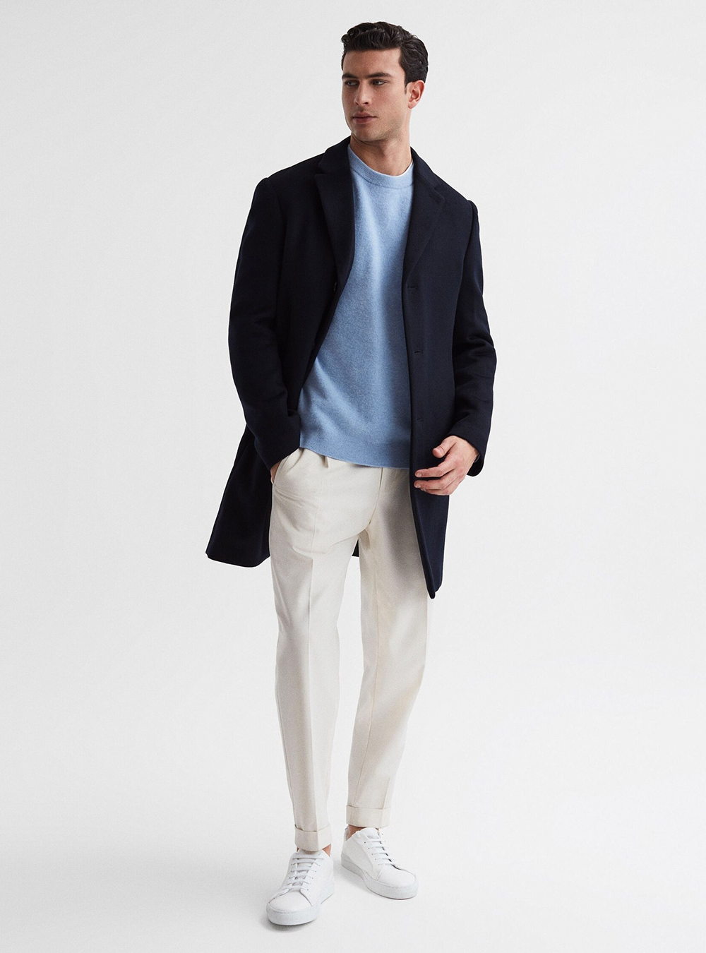 navy overcoat, blue sweater, off-white chinos, and white sneakers