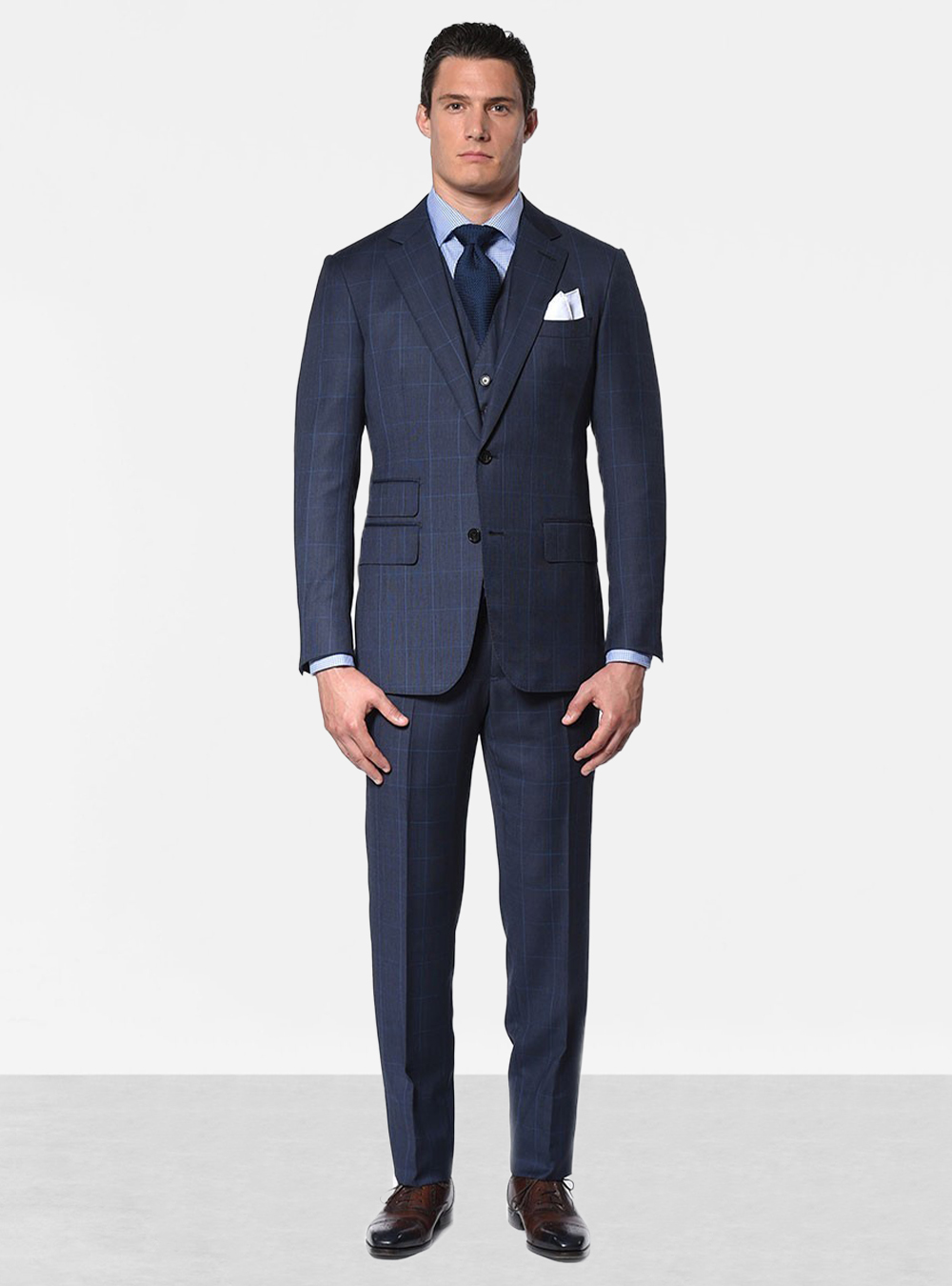 Navy windowpane three-piece suit, light blue dress shirt, navy tie and brown oxford shoes