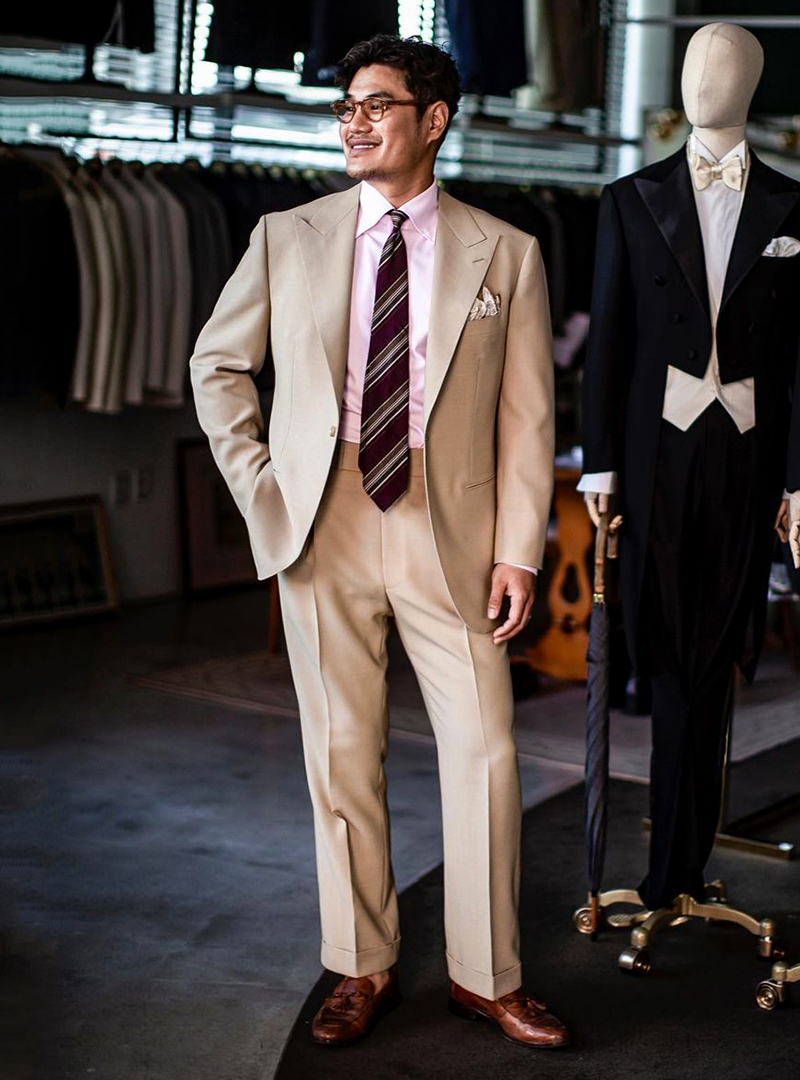 tan suit, pink dress shirt, brown striped tie, and brown loafers