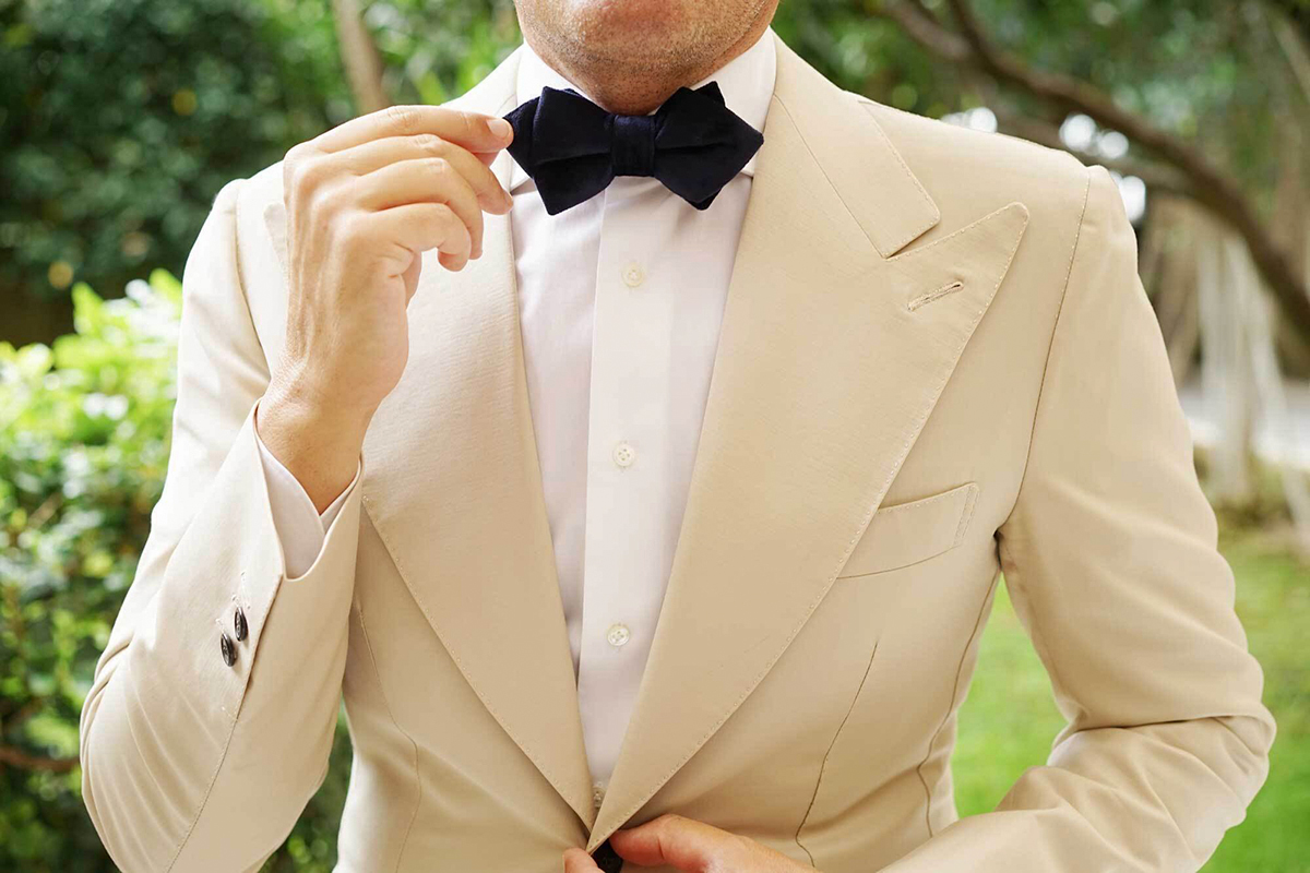 tan suit with a white shirt and black bow tie