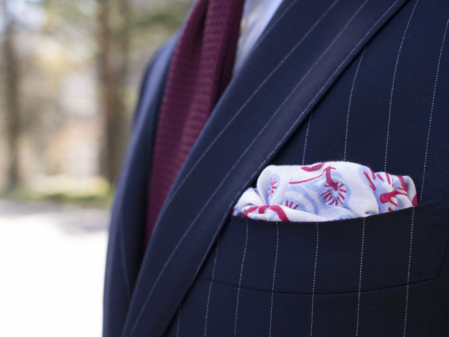 wearing a burgundy tie and floral pocket square