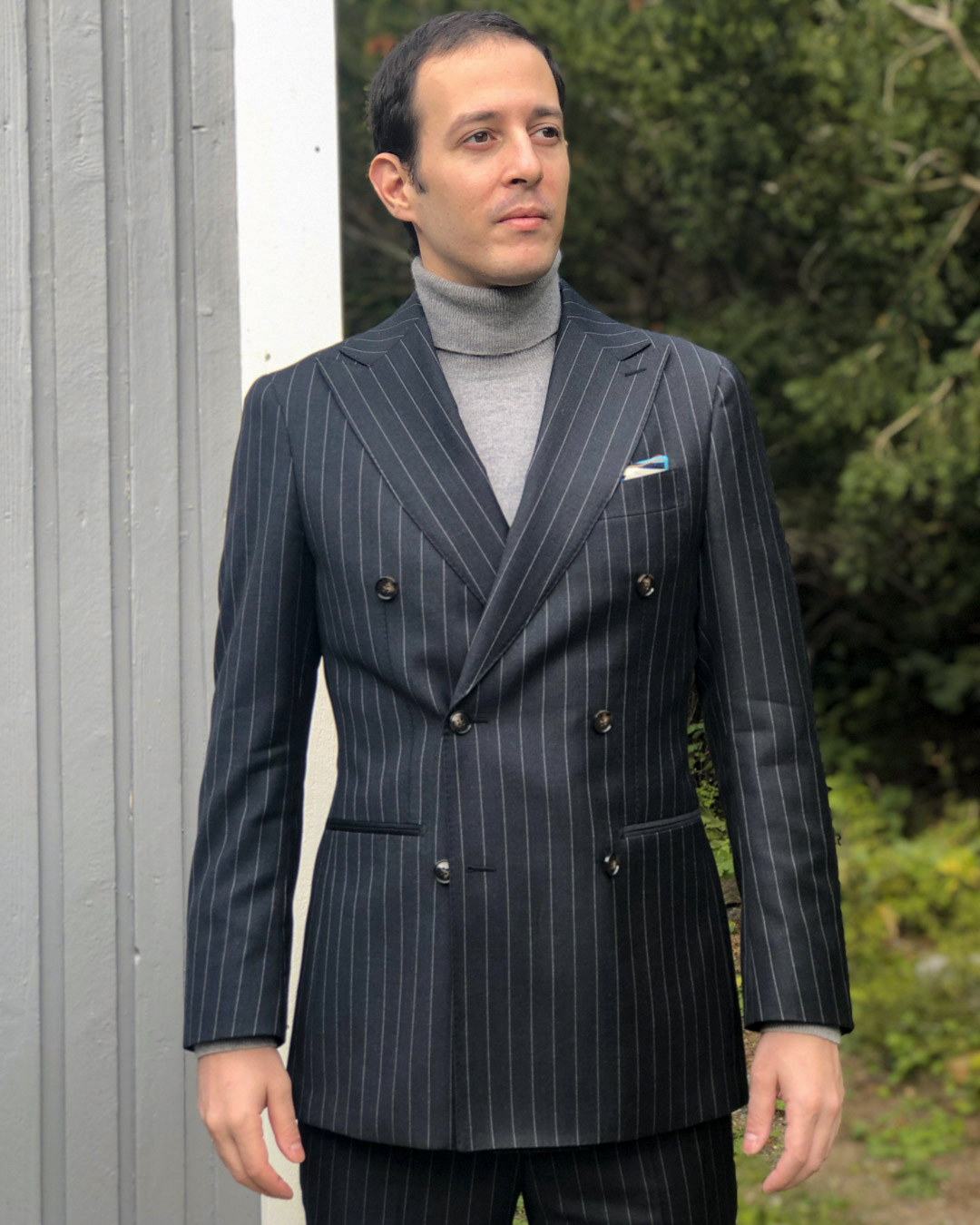 wearing charcoal grey double-breasted pinstripe suit with a turtleneck