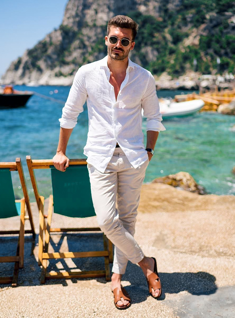 white linen shirt, beige pants, and brown sandals on a beach
